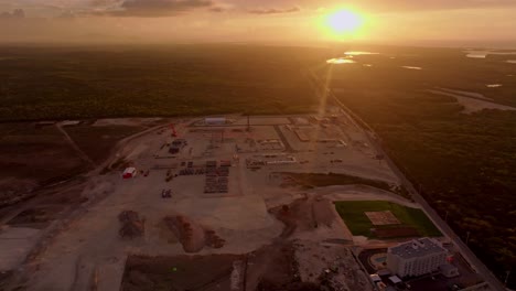 aérea de arriba hacia abajo que muestra un gran sitio de construcción de una moderna central termoeléctrica durante la puesta de sol dorada