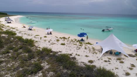 aerial view coastline island people walk barefoot on white sand beach leaving footprints, yacht and beach tents