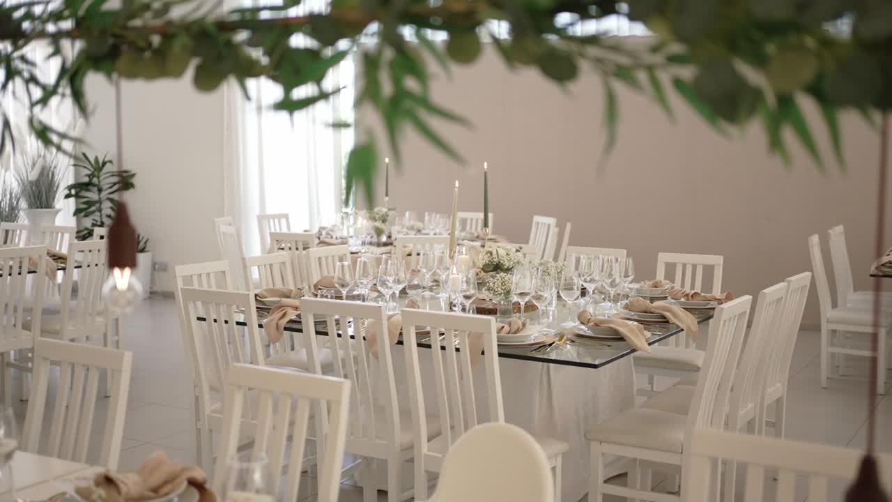 Wedding reception setup with white chairs flowers candles and elegant tableware