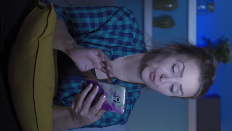 vertical video of woman using social media on phone laughing at night at home.