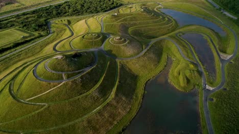 aerial drone footage capturing circular winding roads on green agricultural hills in england, uk, showcasing terraced farmland and lush vegetation
