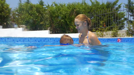 Mujer-Niño-Y-Pelota-En-La-Piscina.