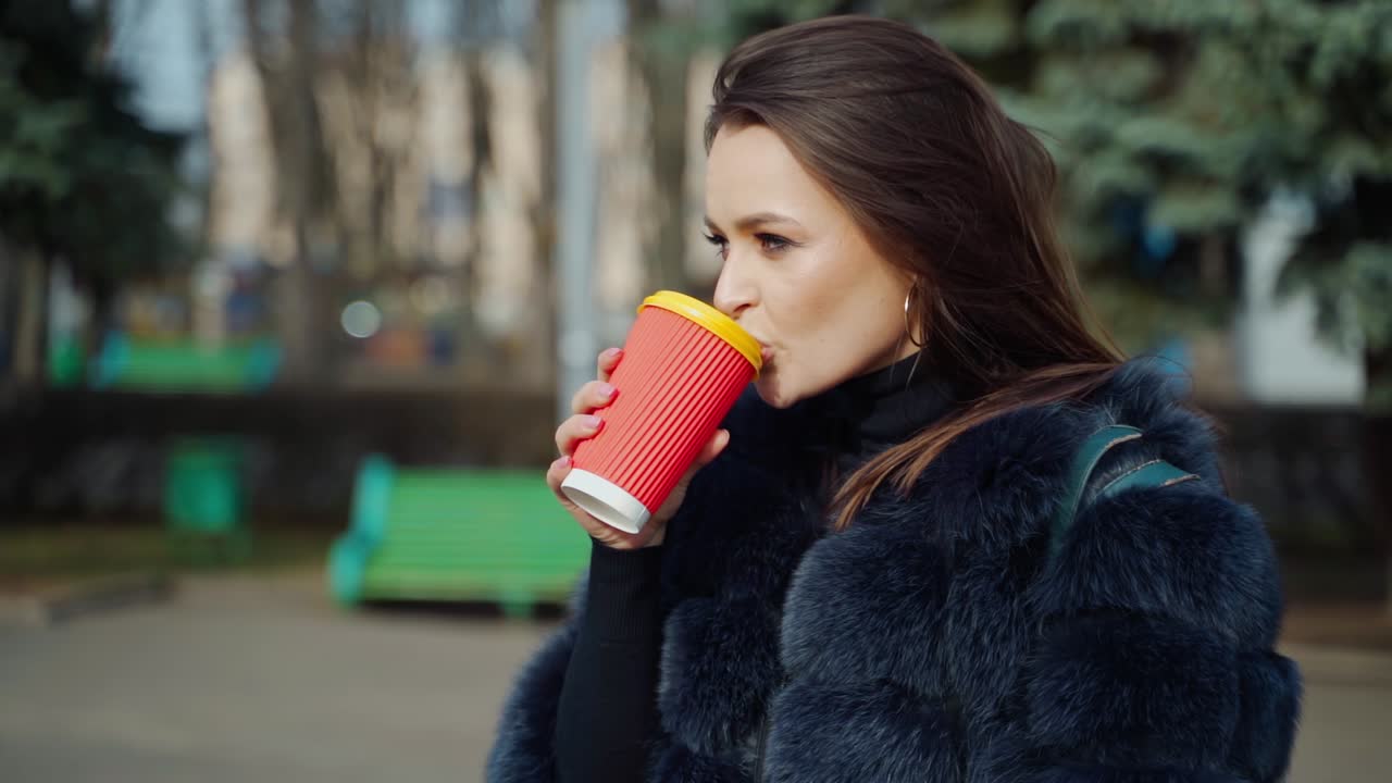 Happy woman with cup of coffee. Pretty young woman drinking coffee on the street of the city