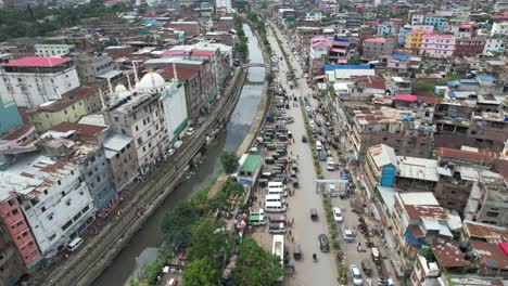 aerial shot of river passing through the city with cars and buildings in the side