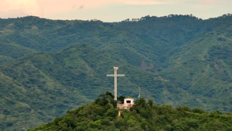 Majestic-cross-monument-on-the-top-of-a-hill-in-Tecalitlan,-lush-green-mountainscape