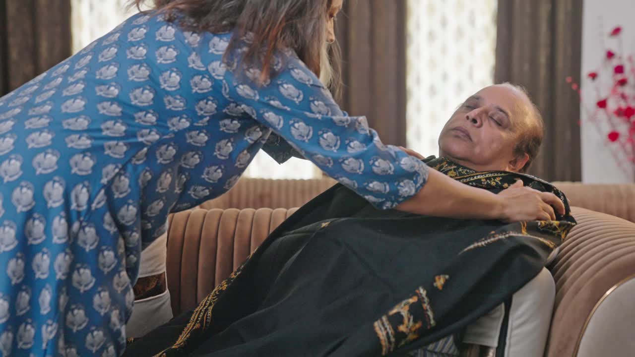 la esposa india le da una manta a su marido mientras él estaba durmiendo