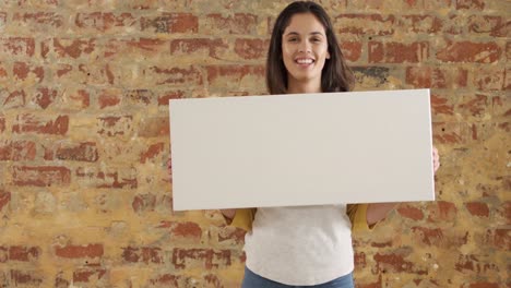mujer caucásica con un rectángulo blanco en una pared de ladrillo