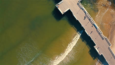 Luftaufnahme-Des-Piers-Mit-Meereswellen,-Die-Zum-Strand-Kommen