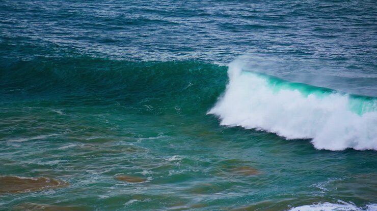 Turquoise ocean wave swelling in slow motion. Foamy powerful barrel rolling