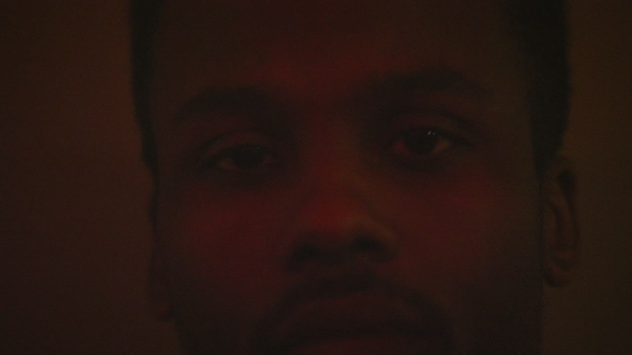 primer plano de la cara del hombre afroamericano mientras sigue con luces de colores parpadeantes