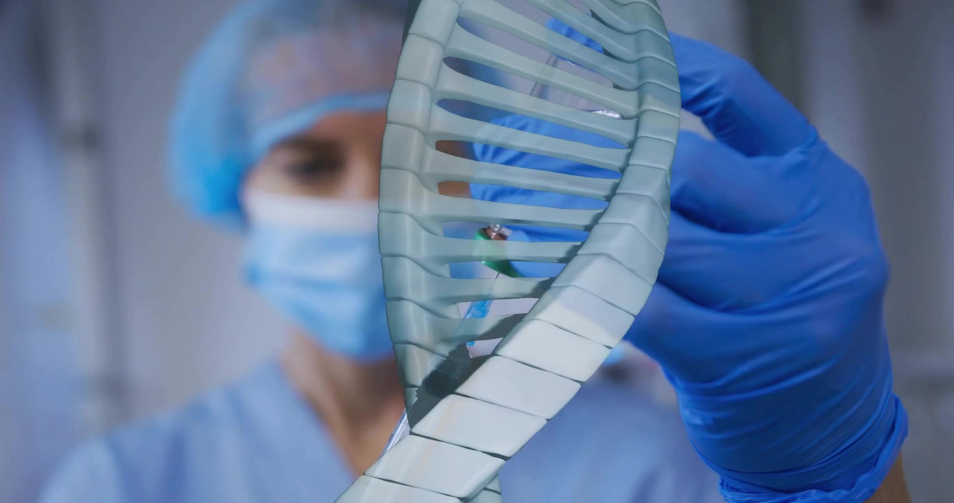 Infermiera che regola la presa, ruotando un'elica di DNA traslucida che rivela una fiala verde in un laboratorio clinico.