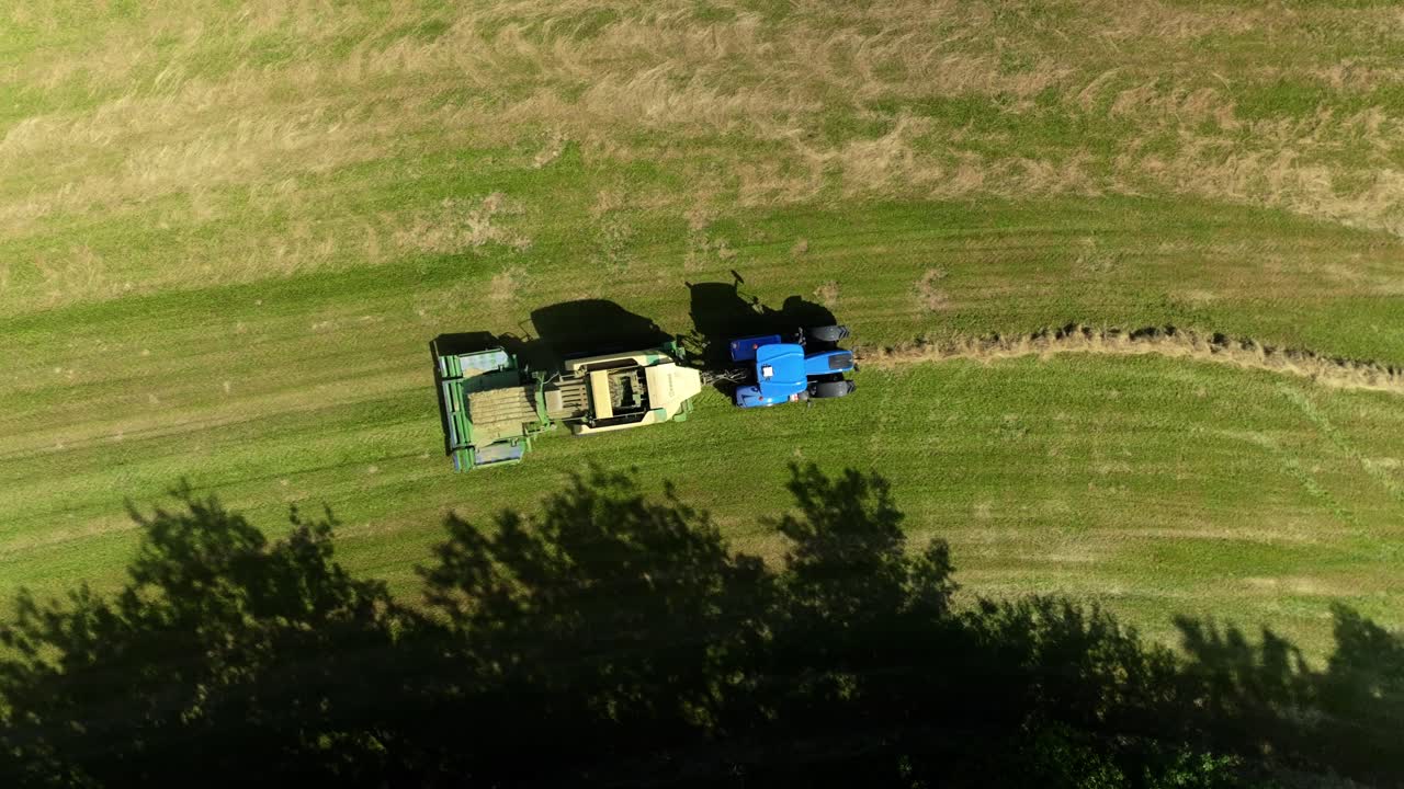 Bird's eye view of a tractor making hay bales. Green meadow in a hot summer in the Czech Republic