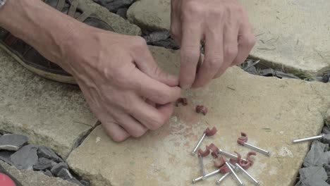 workman hands preparing nails with nail hook cable clip on concrete floor