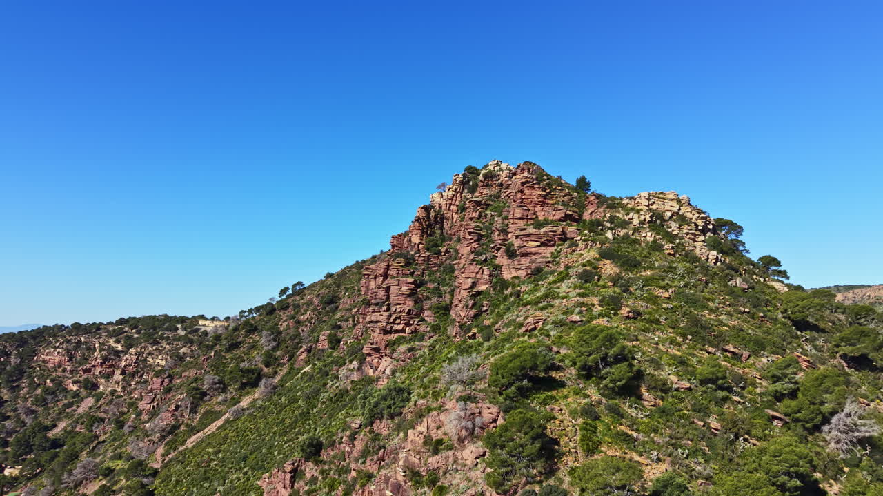 Cima di montagna che domina un paesaggio verde sotto un cielo azzurro e limpido in un pomeriggio soleggiato vicino al paese