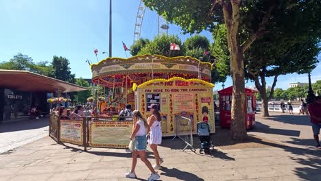 people walking by a carousel in london