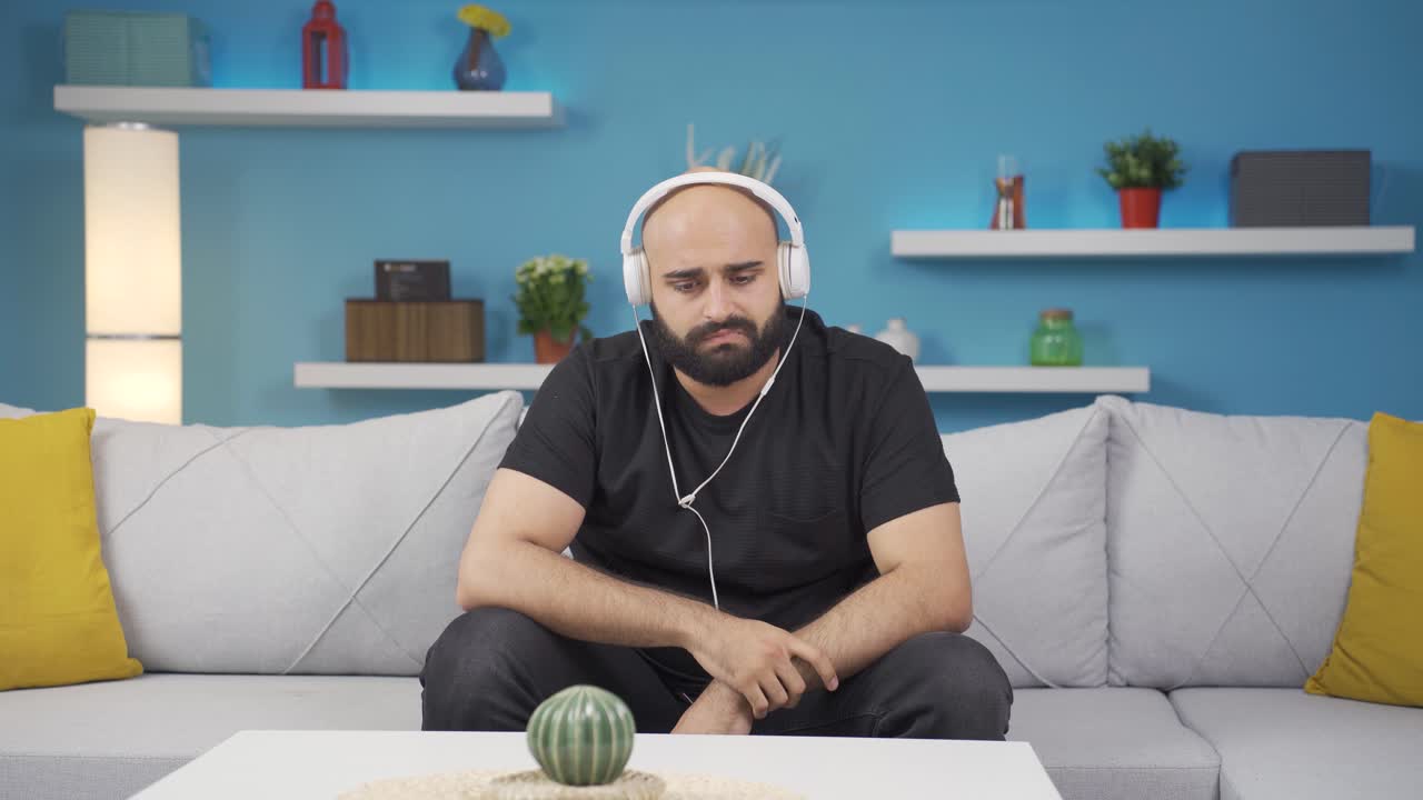 el hombre que escucha música con auriculares es infeliz y triste.