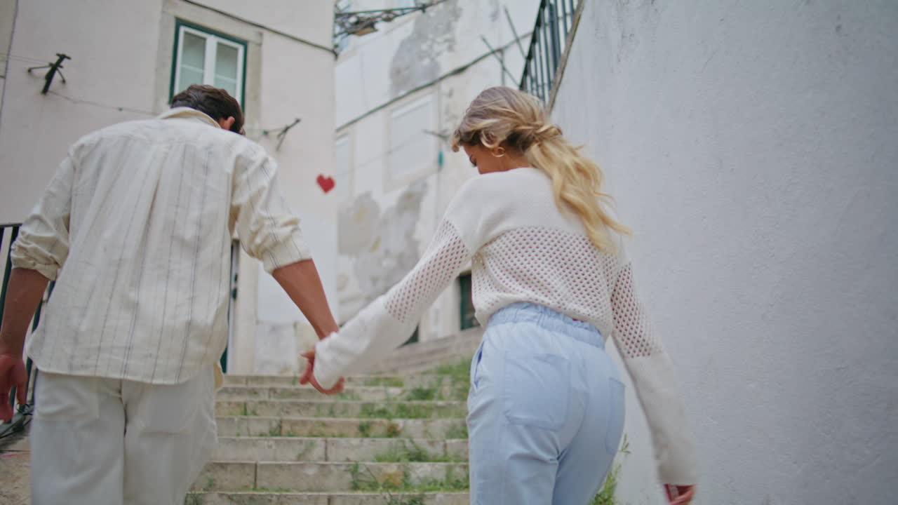 아름다운 연인들은 옛 도시의 뒷면에서 위층을 고 있습니다. 기쁜 신혼 부부가 산책합니다.