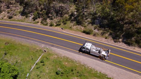 Drone-view-of-truck-driving-on-highway-in-Crackenback,-Australia