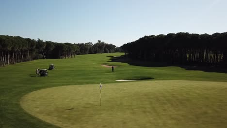 golfer strikes ball and puts it into hole in aerial drone shot