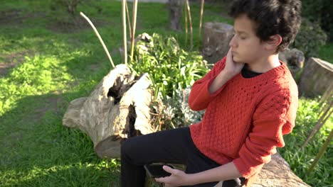 Stressed-adolescent-with-Facial-Scar-Texting-on-Smartphone-in-Backyard