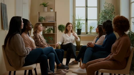 a group of women participating in a support or therapy session, sitting in a circle in a calm indoor setting