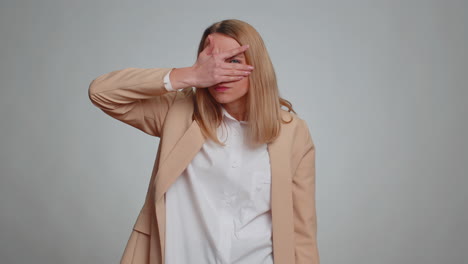 nosy curious business woman closing eyes with hand and spying through fingers hiding and peeping