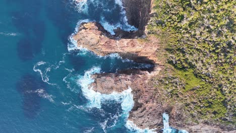 Atemberaubender-Blick-Von-Oben-Auf-Eine-Schroffe-Klippe,-Die-Auf-Das-Turbulente-Azurblaue-Wasser-Trifft:-Der-Kontrast-Der-Natur-Im-Spiel