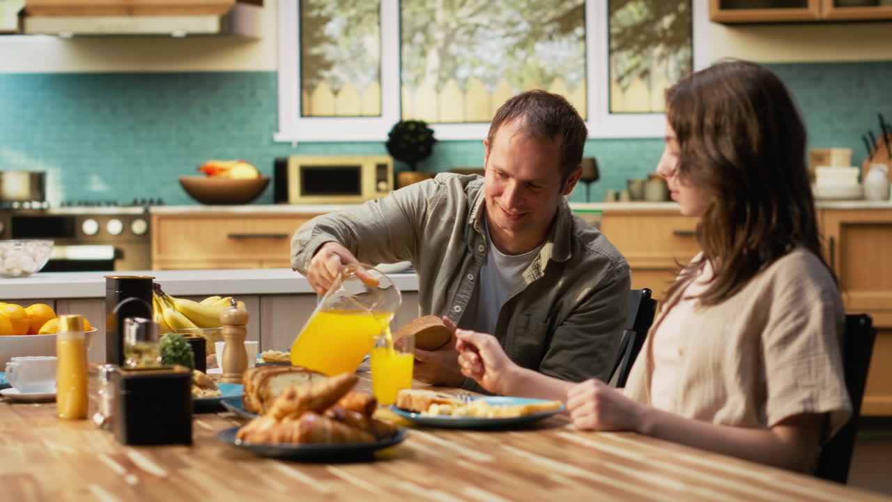 Sweet family sharing croissants and orange juice in the morning