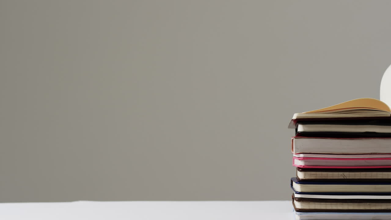 primer plano de un libro abierto en una pila de libros con espacio de copia en fondo gris, en cámara lenta