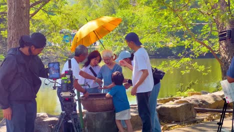 family enjoys filming under a sunny umbrella