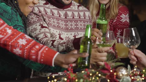 mid section friends toasting drinks in bar during christmas celebrations