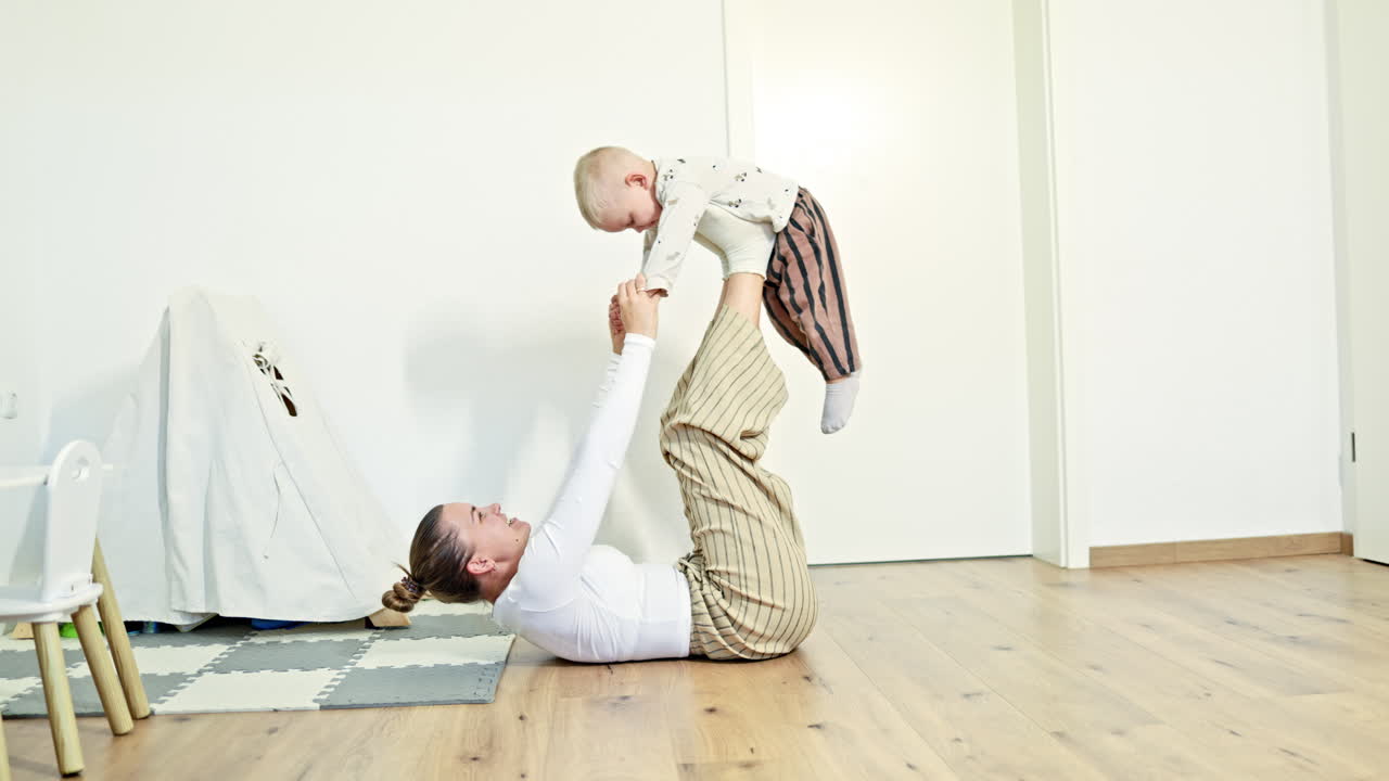 Happy mother amuses her little son, hugs the child. Family games with child, leisure time, motherhood in joy, mother plays active funny game with son