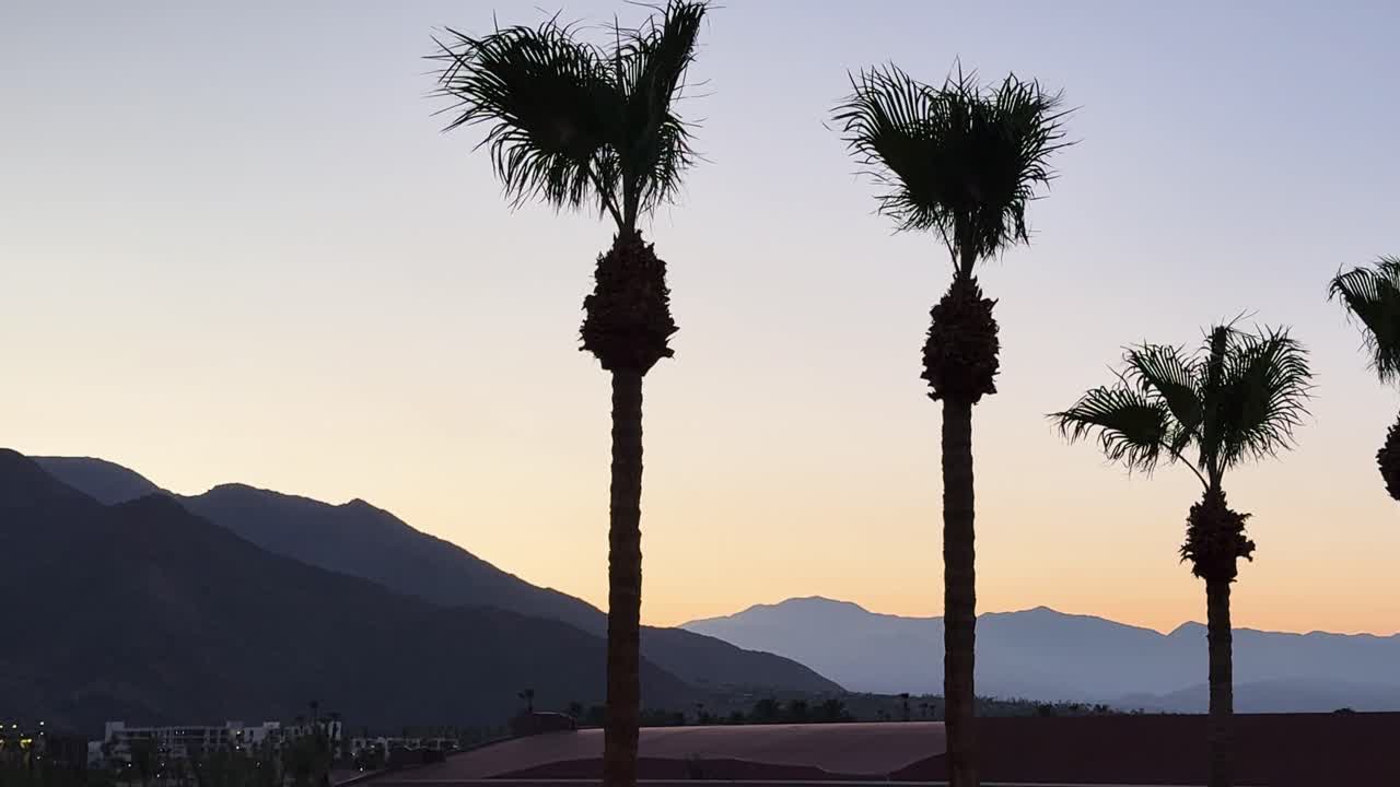 Static shot from Renaissance Hotel in Palm Springs showing palm trees in silhouette and surrounding mountains at sunset