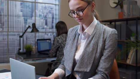 concentrated business woman using laptop sits at office desk workplace web designer online work