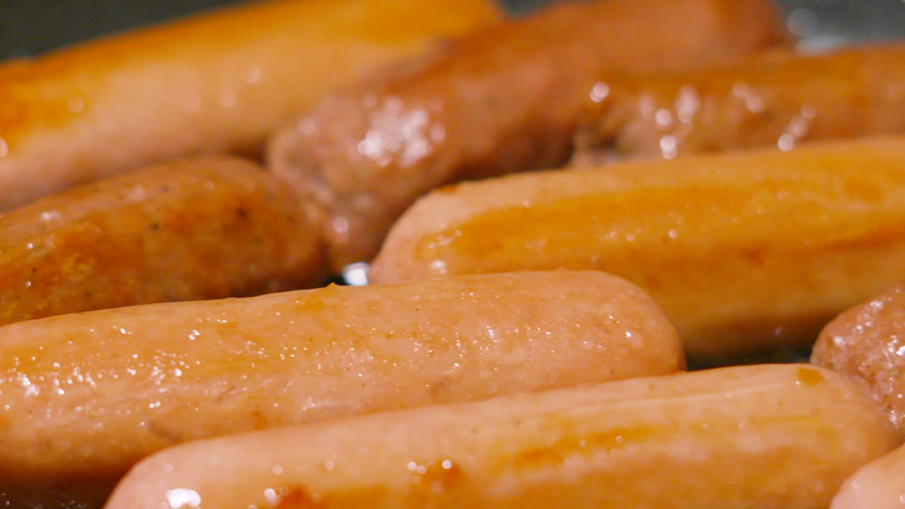 Succulent Meatless Sausages Cooking Gently in Pan as Camera Moves Over Slowly. Carbon Friendly Meat Alternative Food Cooking in Frying Pan. Processed with Natural Ingredients