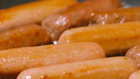 succulent meatless sausages cooking gently in pan as camera moves over slowly. carbon friendly meat alternative food cooking in frying pan. processed with natural ingredients