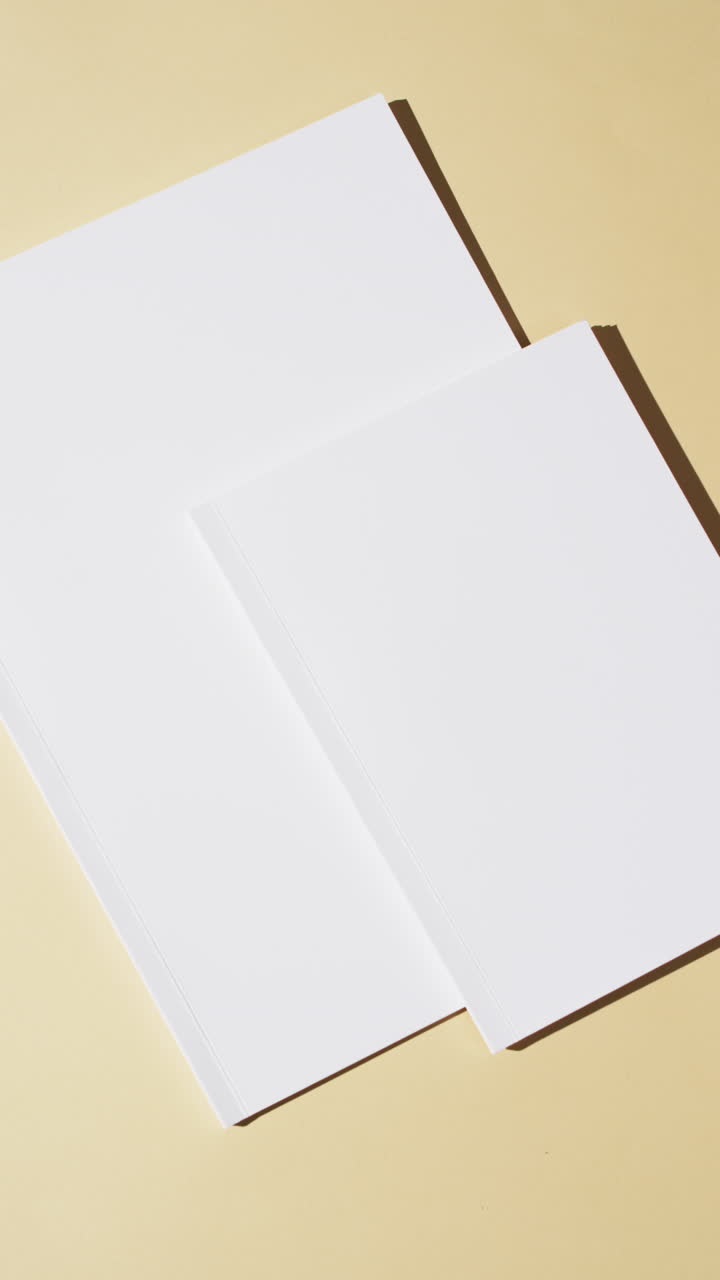 Vertical video of books with blank white pages and copy space on yellow background