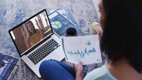 mujer afroamericana sosteniendo un documento haciendo una videollamada en una computadora portátil en casa