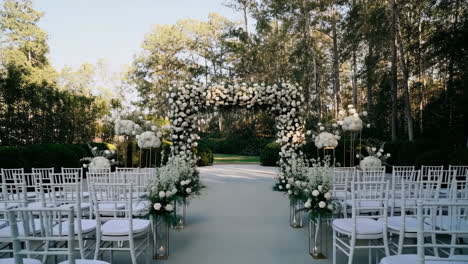 elegant outdoor wedding ceremony setup with white floral arch and aisle