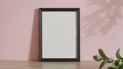 Black-frame-with-copy-space-on-white-background-and-shadow-of-leaf-against-pink-wall