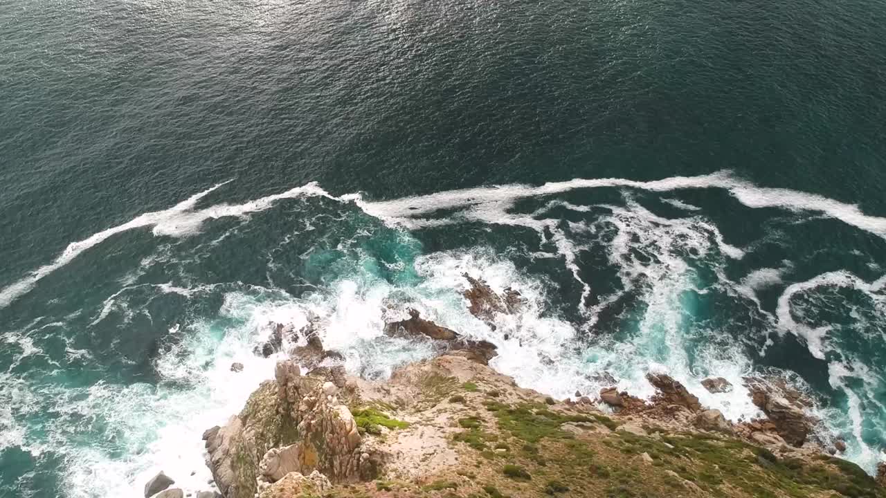 Un drone cattura una splendida vista dall'alto di una costa rocciosa e delle onde dell'oceano che si infrangono su di essa.