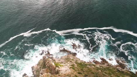 A-drone-captures-a-stunning-top-down-view-of-a-rocky-coast-and-the-ocean-waves-crashing-into-it