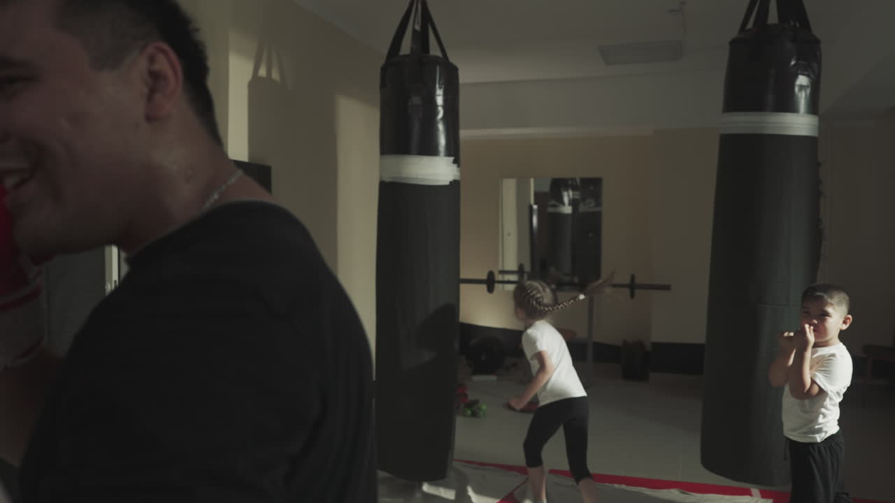 성인과 주니어 권투 선수들은 체육관에서 함께 훈련합니다. 작은 스포츠 선수들은 프로 권투 선수들과 함께 활동적인 수업을 즐기고 있습니다.