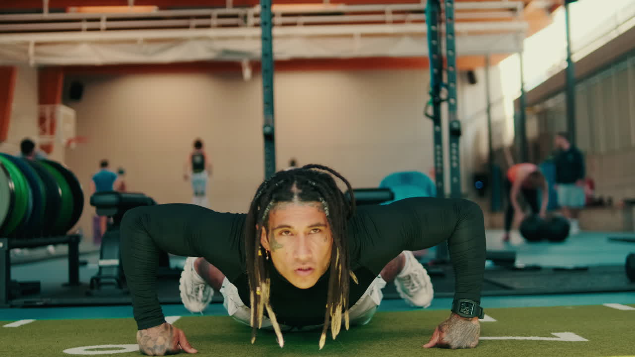 Determined Man with Dreadlocks Doing Push-ups in a Modern Gym