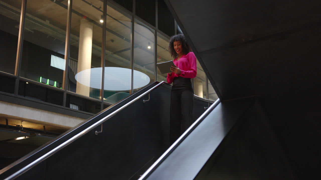 Descendo escadas, mulher usando tablet em um edifício de escritórios moderno, com espaço para texto