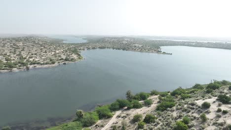 revela una toma cinematográfica del lago botar en sanghar pakistán con un hermoso lago que refleja el sol rodeado de una isla