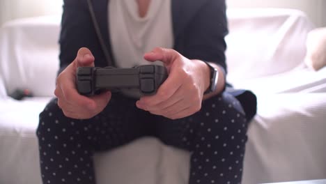 woman's hands using gamepad close-up view playing video console game at home sitting on the sofa