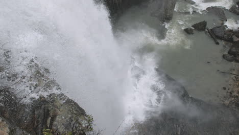 video en cámara lenta siguiendo el agua de una cascada mientras cae a las rocas de abajo