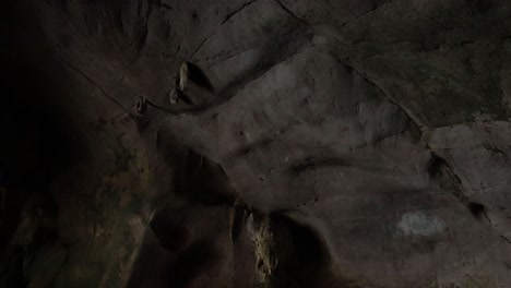 a person explores a dimly lit cave interior.