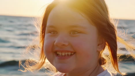 a young girl smiling and laughing by the sea at sunset